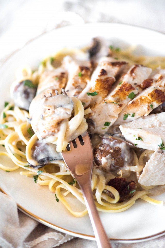 Easy mushroom chicken recipe over pasta on white plate with fork