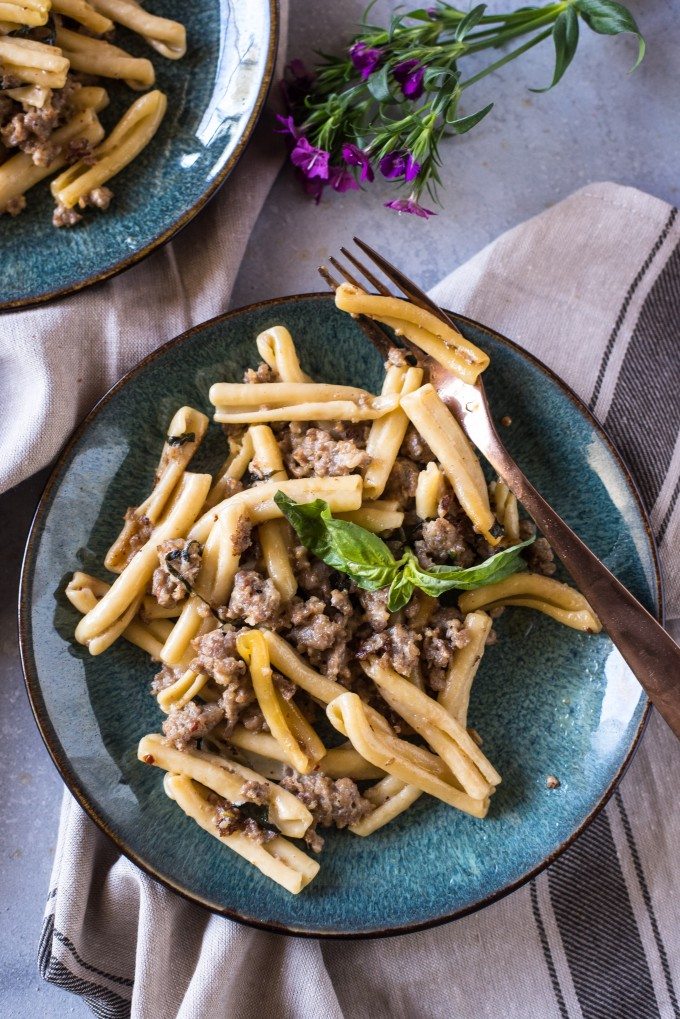 Pasta with Sausage, Basil and Mustard on a blue plate with a fork