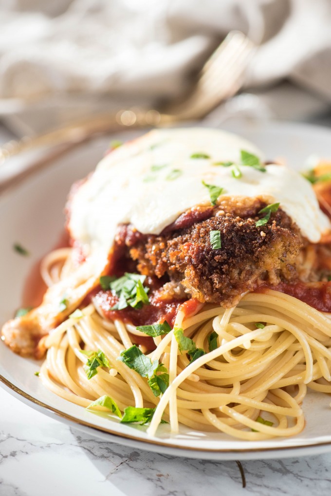 Authentic Veal Parmigiana on white plate with spaghetti