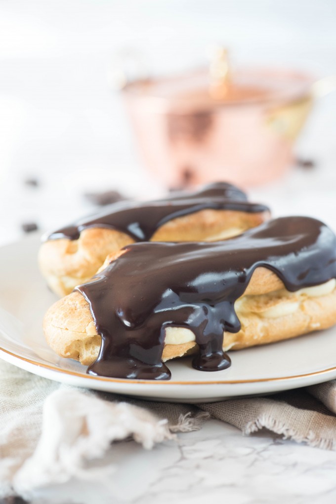 easy eclair recipe with chocolate ganache topping and vanilla pastry filling on white plate on marble slab