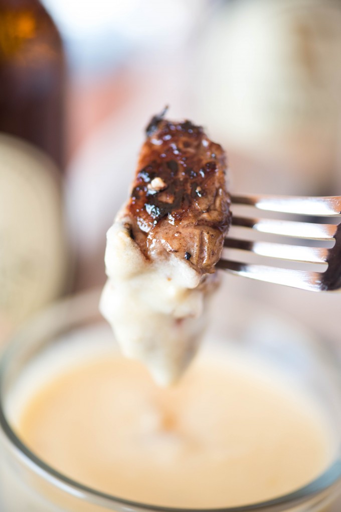 Steak being dipped in cheese fondue