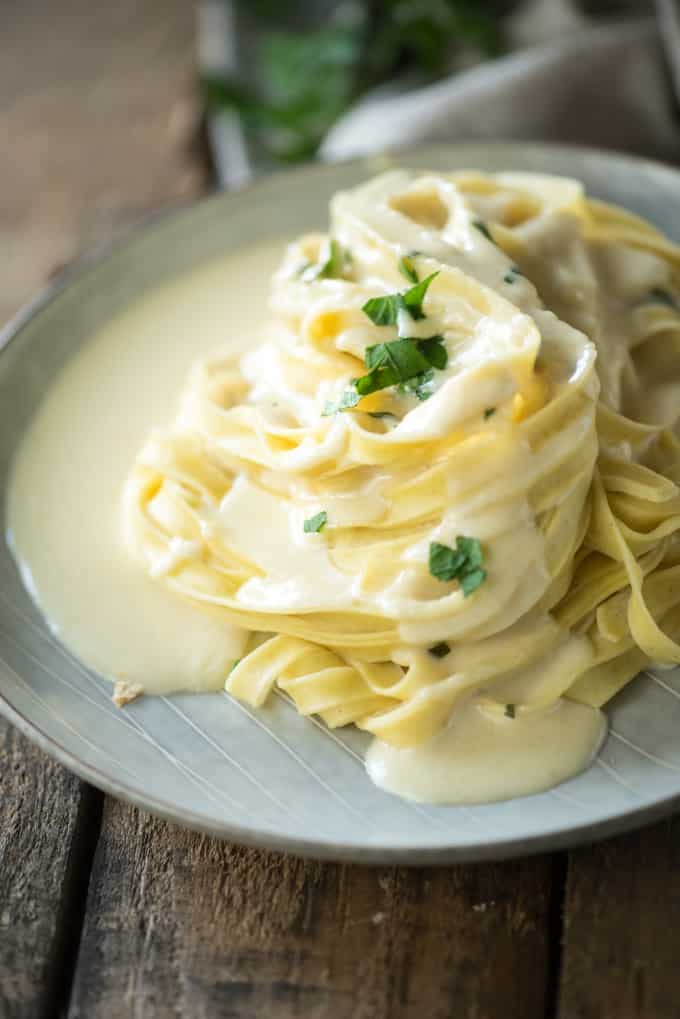 Alfredo sauce on fettuccine on grey plate on wood surface