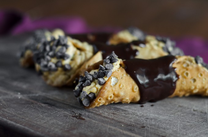 Pumpkin cannolis covered in chocolate on a cutting board