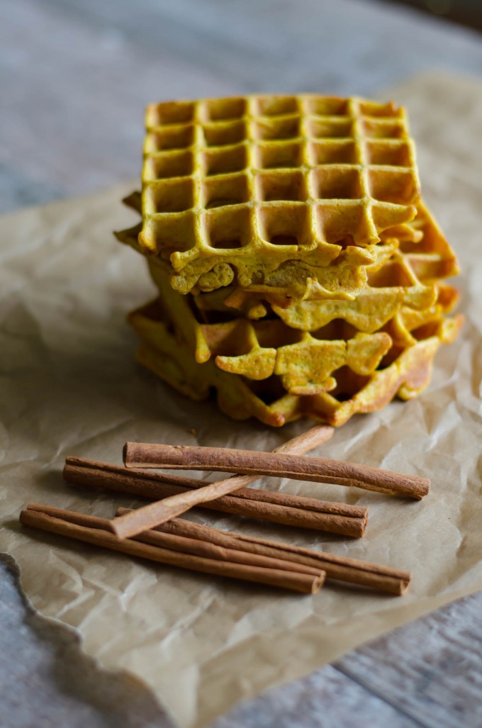 Pumpkin spice waffles on parchment paper with cinnamon sticks