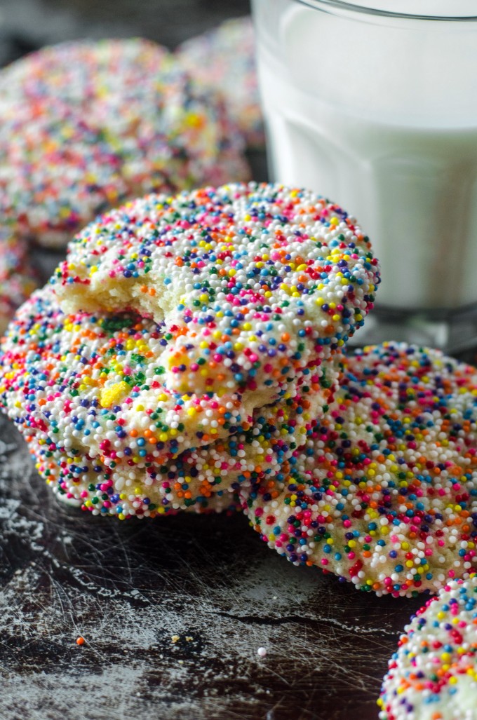Stack of sprinkle cookies with a glass of milk in the background