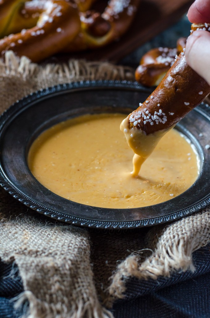 Hot pretzel dipping into beer cheese dipping sauce