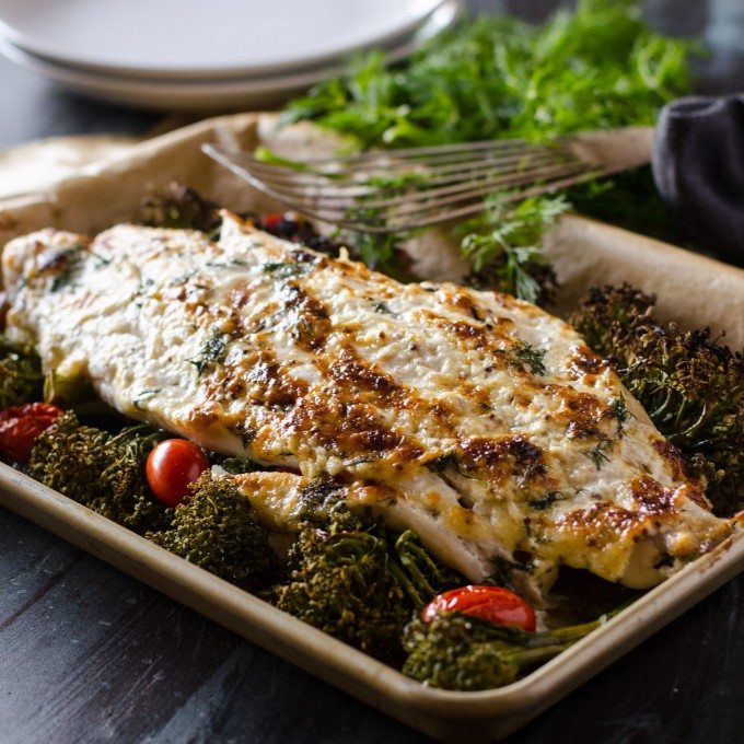 baked grouper on a pan with tomatoes and broccolini