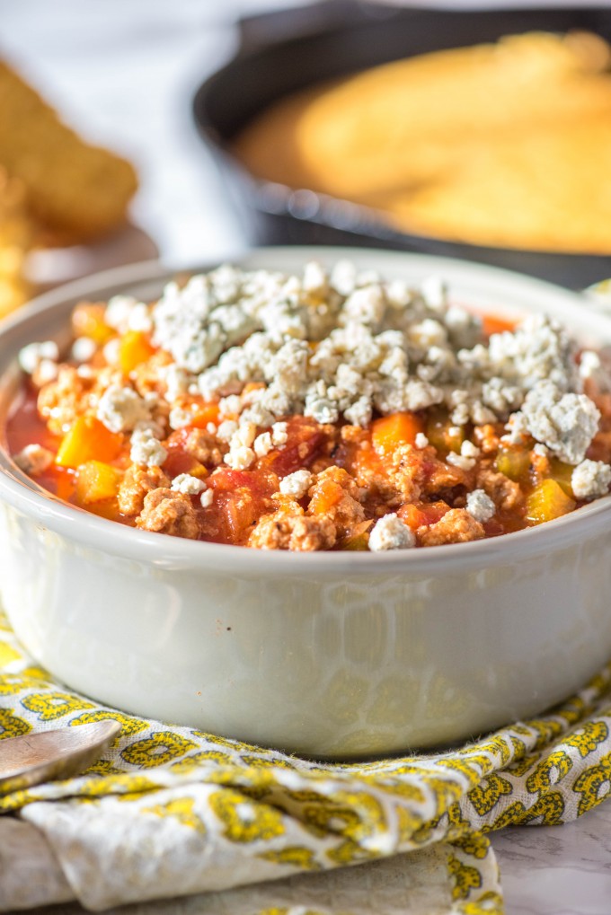 Slow Cooker Crockpot Buffalo Chicken Chili in gray bowl with yellow napkin and cornbread