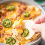 Close up of chip dipping into jalapeno popper dip