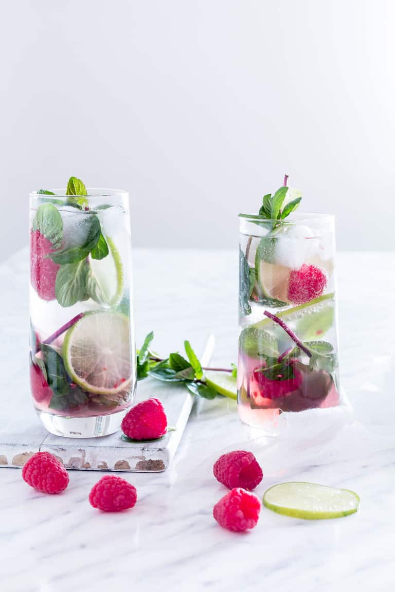 Two raspberry mojitos with raspberry and mint