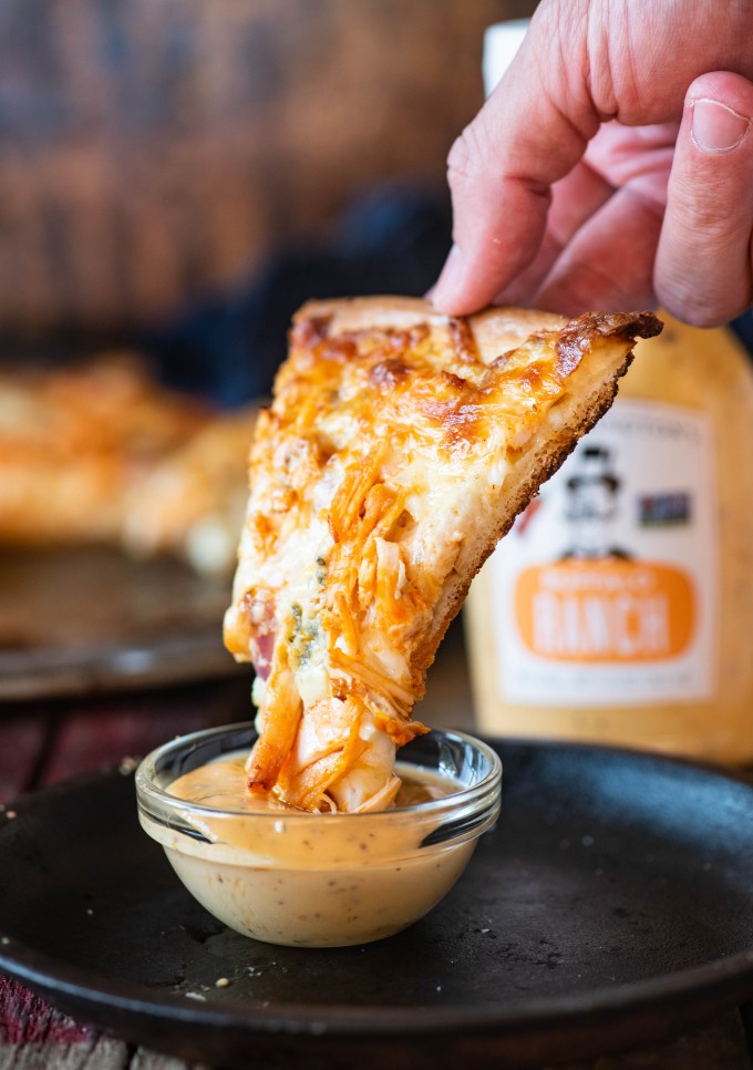 Dipping buffalo chicken pizza into buffalo ranch 