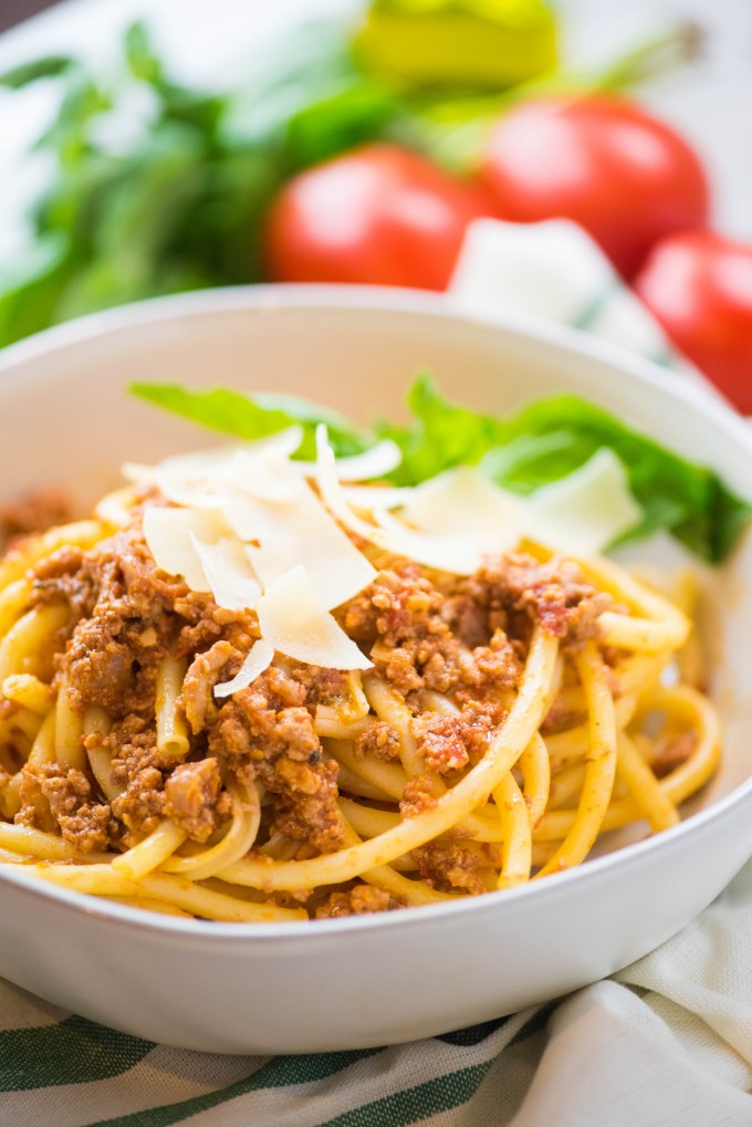 Slow cooker bolognese over pasta in a white bowl