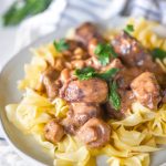 Instant pot beef tips over egg noodles on a white plate