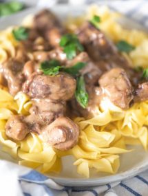 Close up of instant pot beef tips over egg noodles on a white plate