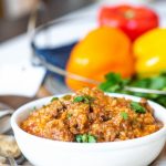 Stuffed pepper soup in a white bowl with peppers in the background