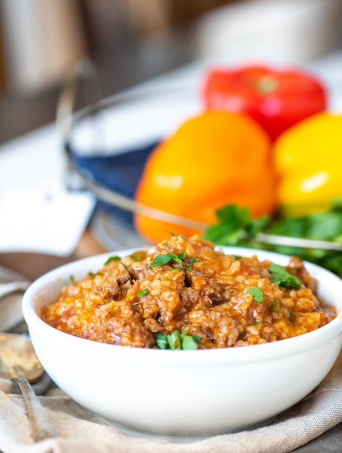 Stuffed pepper soup in a white bowl with peppers in the background