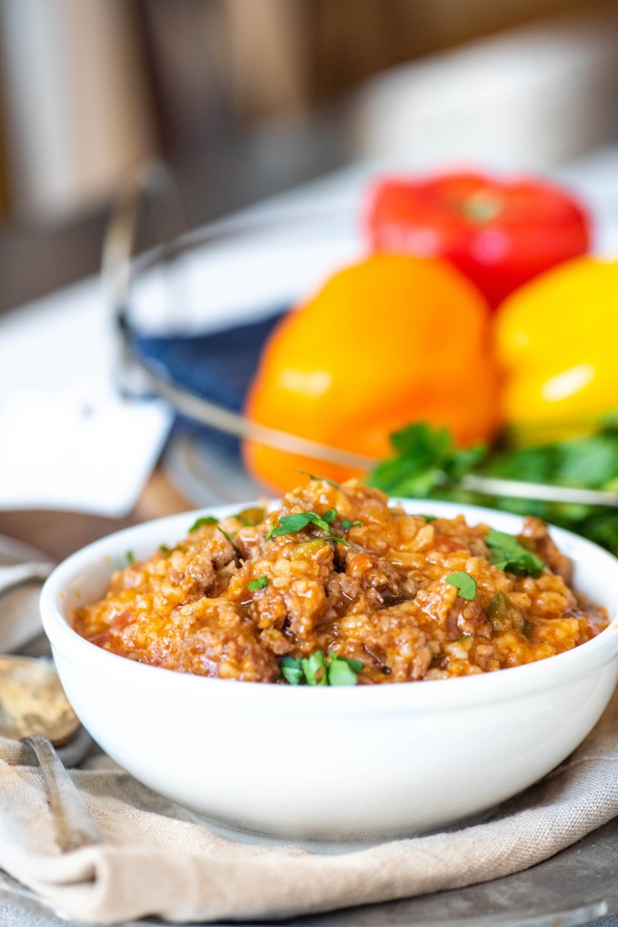 Stuffed pepper soup in a white bowl with peppers in the background