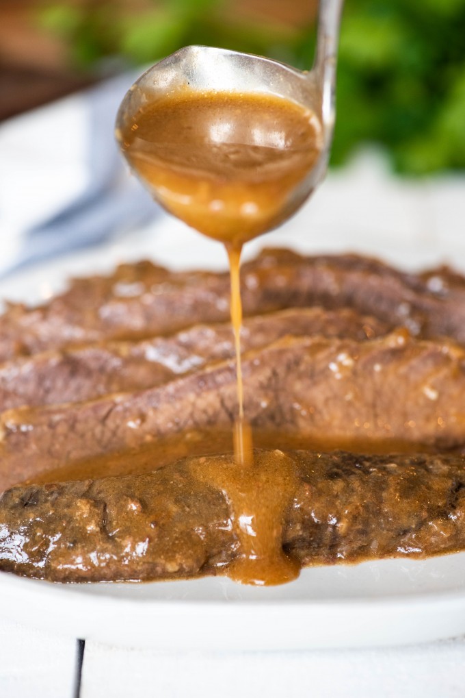 Gravy being poured onto brisket slices