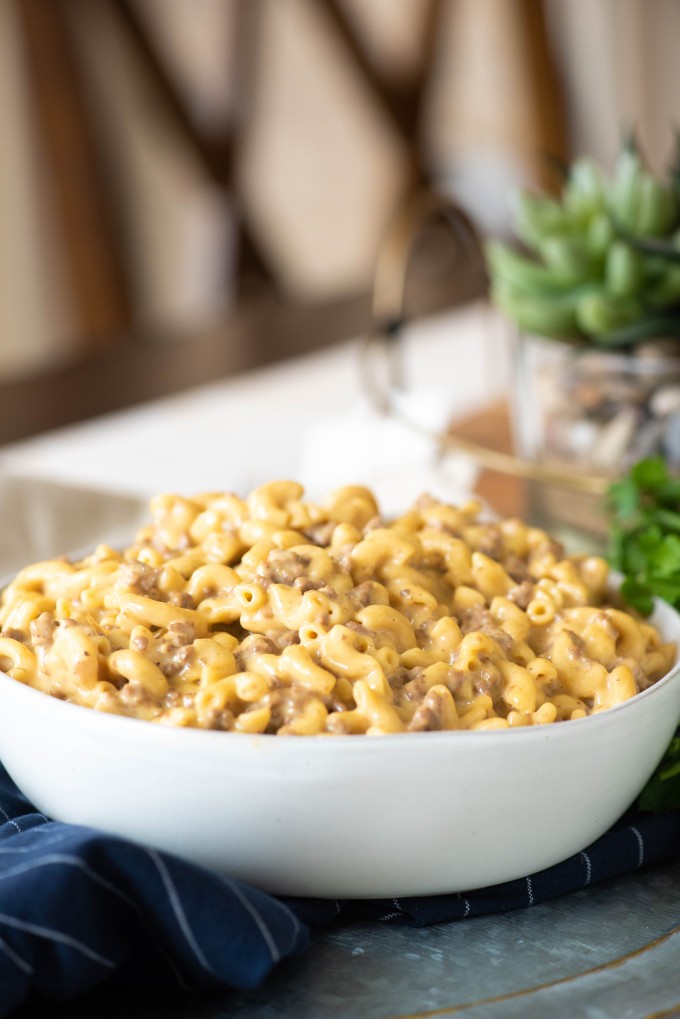 This easy Instant Pot Cheeseburger Mac and Cheese is a homemade version of your favorite boxed meal. Made with a mixture of Velveeta and cheddar cheese, this casserole is sure to become one of your family's new favorite dinners! #gogogogourmet #instantpotcheeseburgermac #cheeseburgermacandcheese #copycatrecipes #easydinnerrecipes #easyinstantpotrecipes Cheeseburger mac in a white bowl