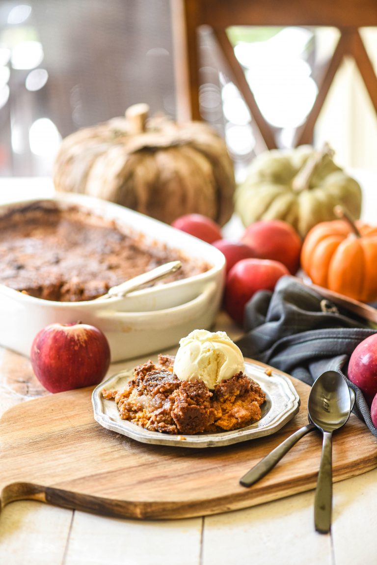 Apple Pumpkin Dump Cake on a butting board with apples and pumpkins