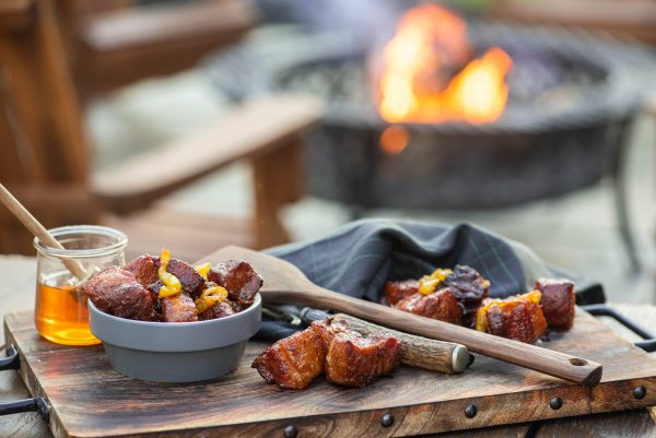 Spicy pork belly burnt ends with a fire in the background 