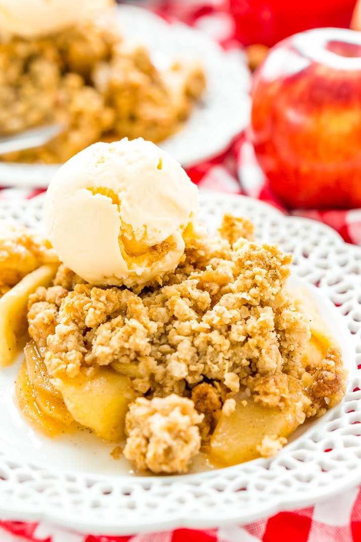 Apple crisp topped with ice cream on a plate